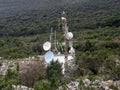 Radio retranslator tower with satellite dish antennas on green hillside Royalty Free Stock Photo