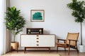 Radio on white cupboard between ficus tree and wooden armchair against white wall with gallery in retro living room interior Royalty Free Stock Photo