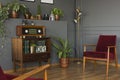 Radio on wooden cabinet next to plant and red armchair in grey v