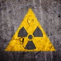 Radioactive atomic ionizing radiation danger warning symbol in triangular yellow shape painted massive cracked concrete wall