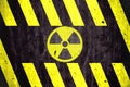 Radioactive ionizing radiation danger symbol with yellow and black stripes painted on a massive concrete wall