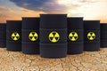 Radioactive waste against sky clouds and dried depleted land. Radioactive waste barrels. Environment protection