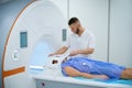 Radiographer preparing man for brain magnetic resonance imaging procedure