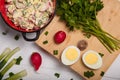 Radish, green onions, parsley, eggs salad in red bowl. Some fresh vegetables and greenery on chopping board. Healthy eating Royalty Free Stock Photo