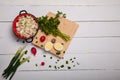 Radish, green onions, parsley, eggs salad in red bowl. Some fresh vegetables and greenery on kitchen chopping board on white Royalty Free Stock Photo