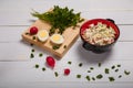 Radish, green onions, parsley, eggs salad in red bowl. Some fresh vegetables and greenery on kitchen chopping board on white Royalty Free Stock Photo