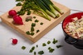 Radish, green onions, parsley, eggs salad in red bowl. Some fresh vegetables and greenery on kitchen chopping board Royalty Free Stock Photo