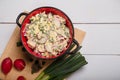 Radish, green onions, parsley, eggs salad in red bowl. Some fresh vegetables and greenery on kitchen chopping board Royalty Free Stock Photo