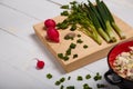 Radish, green onions, parsley, eggs salad in red bowl. Some fresh vegetables and greenery on kitchen chopping board Royalty Free Stock Photo