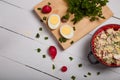 Radish, green onions, parsley, eggs salad in red bowl. Some fresh vegetables and greenery on kitchen chopping board Royalty Free Stock Photo