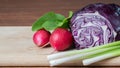 Radishes, kolbari cabbage and green onions on a wooden board close-up