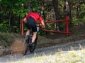 Cyclist goes through open gate bar into terrain in forest