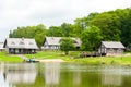 RADVILISKIS, LITHUANIA - JUNE 12, 2014: Unique Village and Rural Area in Lithuania with Wooden Building and Green Grass. Lake with