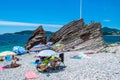 Resting people on pebble public stone beach with beautiful puff rocks. Rafailovici, Montenegro