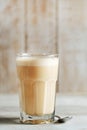 Raff coffee in a glass transparent glass on a light wood background. coffee with milk