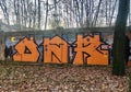 Raffiti in the form of orange letters on a stone wall in an abandoned Park