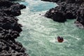 Raft with team is sailing on dangerous rapids among rocks on mountain river