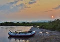 A raft moored on a sandy beach under a midnight sun.