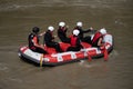 Rafting team members and instructor rowing in their boat down the murky river during a summer day Royalty Free Stock Photo