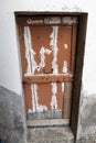 Ragged brown wooden door in a stone wall close-up of village house. Italy . Royalty Free Stock Photo