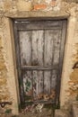 Ragged brown wooden door in a stone wall close-up of village house. Italy .