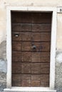 Ragged brown wooden door in a stone wall close-up of village house. Italy . Royalty Free Stock Photo