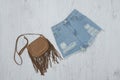 Ragged denim shorts and a brown handbag. Fashionable concept. Royalty Free Stock Photo