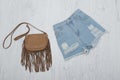 Ragged denim shorts and a brown handbag. Fashionable concept. Royalty Free Stock Photo