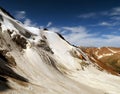 Ragged glacier flows from rocky edge of the mountain under amazing blue sky