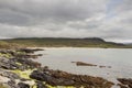 Ragged stone coast line and mountains under low cloudy sky, Silver strand, county Mayo, Ireland. Irish nature background and