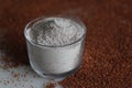 Ragi flour in a glass bowl along with a scattered spread of ragi grains around