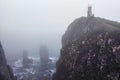 Raging sea, rocks, lighthouse and heavy fog