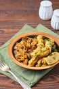 Ragout, stewed beef with cabbage and dough dumplings in a ceramic plate on brown wooden background. Cabbage recipes