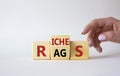 Rags vs Riches symbol. Businessman hand points at wooden cubes with words Rags and Riches. Beautiful white background. Rags vs Royalty Free Stock Photo