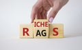 Rags vs Riches symbol. Businessman hand turns wooden cubes and changes the word Rags to Riches. Beautiful white background. Rags Royalty Free Stock Photo