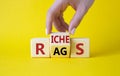 Rags vs Riches symbol. Businessman hand turns wooden cubes and changes the word Rags to Riches. Beautiful yellow background. Rags Royalty Free Stock Photo
