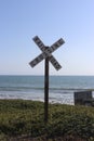 Rail Road Crossing Sign with Ocean and Blue Sky Background Royalty Free Stock Photo