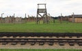 Rail tracks, guard tower, barbed wire fence and barracks of Auschwitz concentration camp Royalty Free Stock Photo