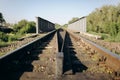Rail tracks over the bridge in the green field. Railway transport industry. Empty road on summer day Royalty Free Stock Photo