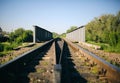 Rail tracks over the bridge in the green field. Railway transport industry. Empty road on summer day Royalty Free Stock Photo