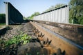 Rail tracks over the bridge in the green field. Railway transport industry. Empty road on summer day Royalty Free Stock Photo