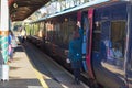 Railway train conductor waves a signal to a station platform guard.