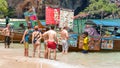 Railay, Krabi / Thailand: a group of tourists stands in sea surf and watches menus of a boat restaurant