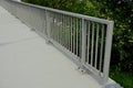 Railing at the bridge with vertical fence bars anchored to the ground with four concrete screws. plastic caps