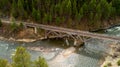 Railroad bridge over a wild Idaho river with a lush green forest