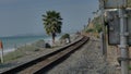 Railroad at California coast train moving between palms next to ocean pacific surfliner in San Clemente