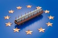 Railroad car with stack of rolled metal products on flag of the EU. Production and trade of metal products in European Union, Royalty Free Stock Photo