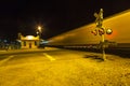 Railroad crossing with passing train by night Royalty Free Stock Photo