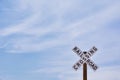 Railroad crossing sign against blue sky background. Royalty Free Stock Photo