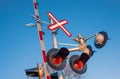 Railroad crossing traffic sign with red lights and barrier. Railroad crossing sign against blue sky background Royalty Free Stock Photo